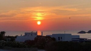 A sunset over a coastal area with buildings in the foreground. - Sunset Villa II (Paros)