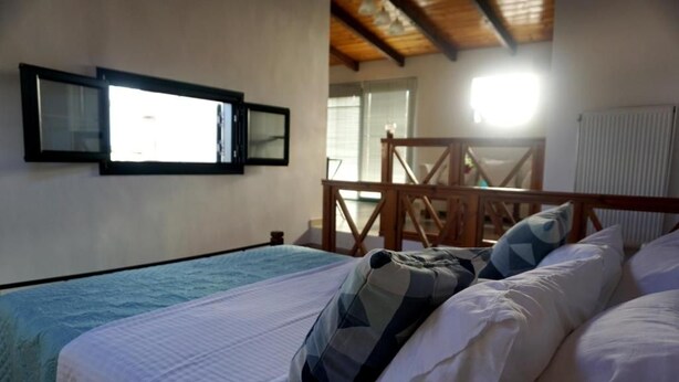 A bedroom with a bed, a wooden headboard, a window, and a radiator. - Garden House (Kalamata)