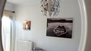 A living room with a grey sofa, a white coffee table, a modern chandelier, and a framed picture of a boat on the wall. - Garden House (Kalamata)