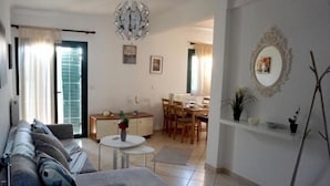 A living room with a sofa, a dining table, and a chandelier. - Garden House (Kalamata)