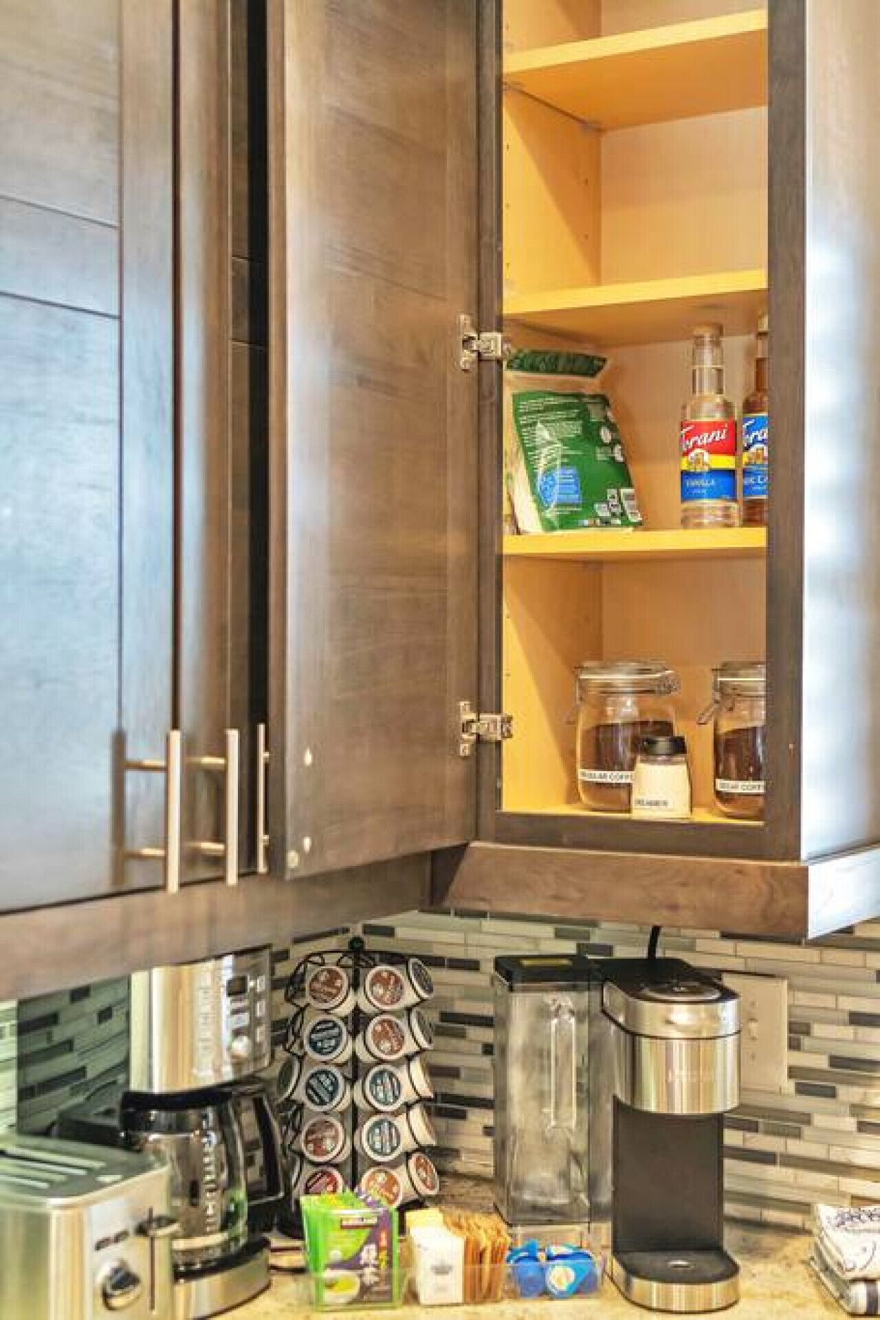 A kitchen with dark wooden cabinets, a coffee machine, a blender, and various food items on the counter.