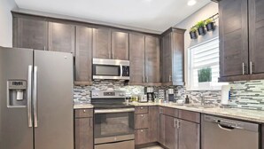 Una cocina moderna con electrodomésticos de acero inoxidable, gabinetes de madera oscura y salpicadero de azulejos.