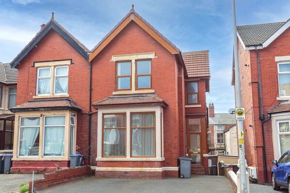 A red brick house with two bay windows and a small porch.