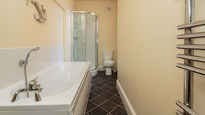A bathroom with a bathtub, glass shower enclosure, toilet, and a towel rack. - Cherry Property - Coconut Suite (Blackpool)