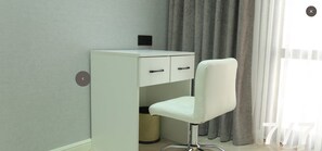 Compact room with a minimalist design, featuring a desk with two drawers and a chair.