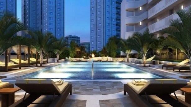 A rooftop pool area with lounge chairs and palm trees, surrounded by high-rise buildings. - Deluxe 2BR Condo in Waikiki! (Honolulu)