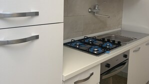 A kitchen with white cabinets, a gas stove, a range hood, and a built-in oven.