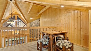 Un interior de madera con techo alto, pared de piedra y vista por una ventana.