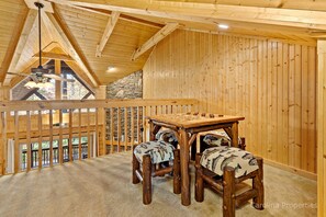 A wooden interior with a high ceiling, a stone wall, and a view through a window.