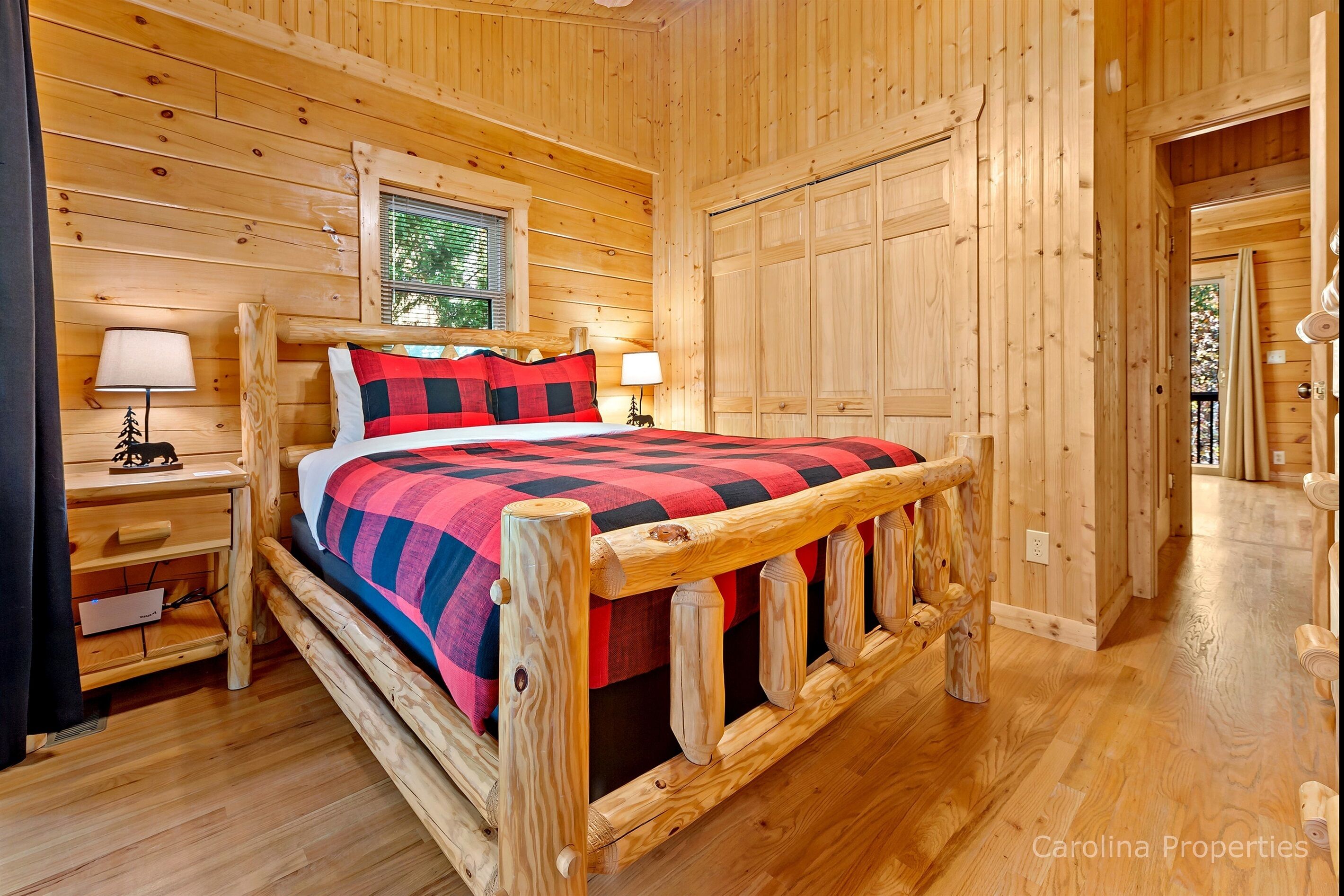 A wooden cabin bedroom with a bed, nightstands, and a window.