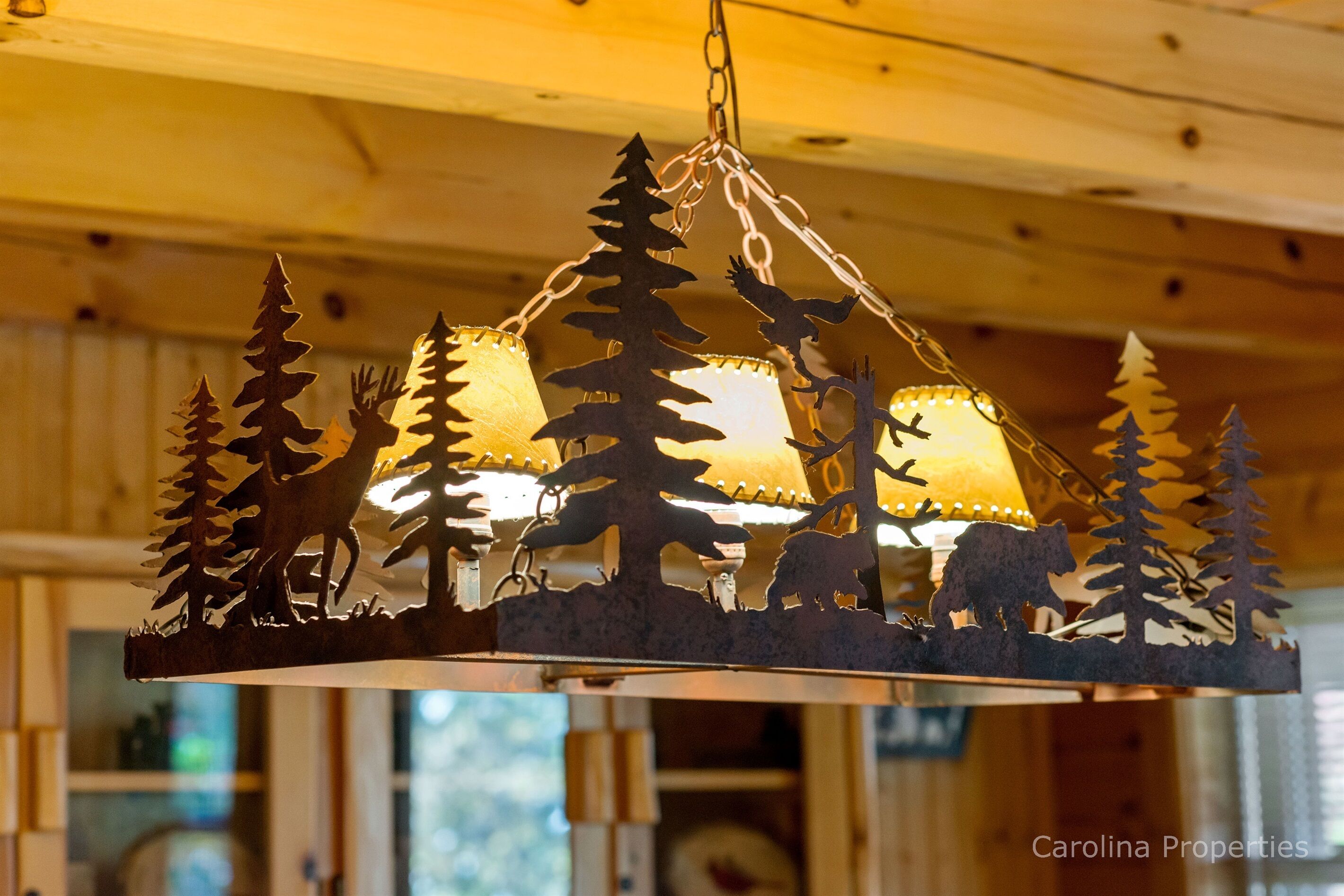 A metal outdoor light fixture with tree and animal silhouettes.