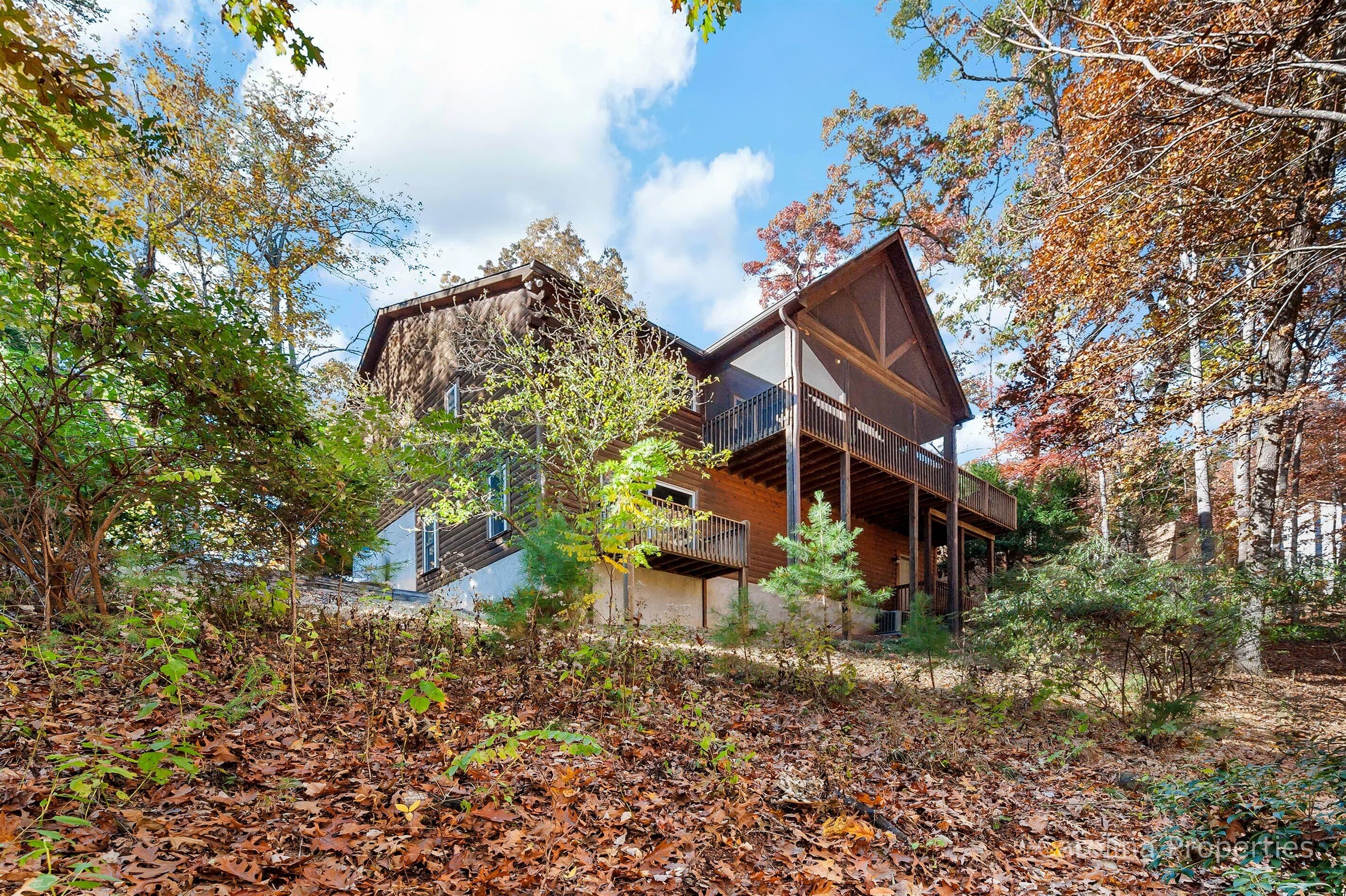 A modern house with a wooden deck and a large window overlooking a forested area.