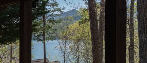 Vista des d'una finestra d'una cabana amb vista a un llac rodejat d'arbres i una muntanya.