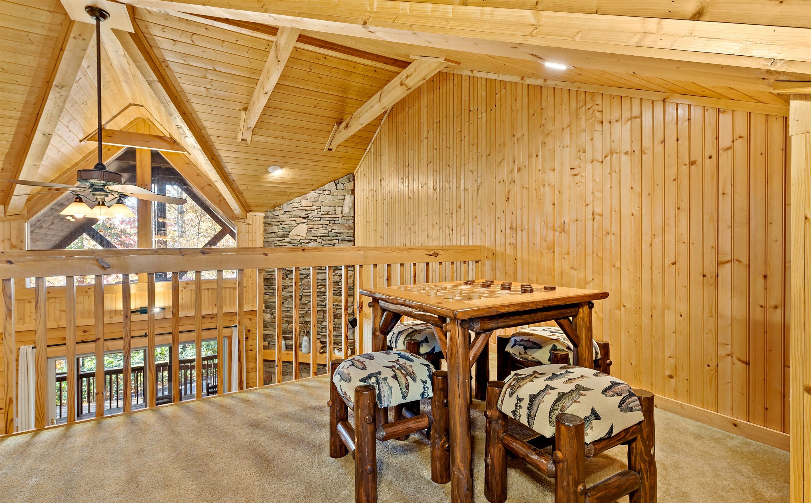 A wooden interior with a high ceiling, a stone wall, and a view through a window.