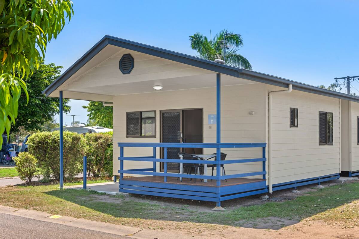 A small, single-story building with a covered porch and a small table and chairs.
