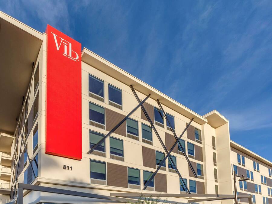 Un edificio moderno con un llamativo letrero rojo 'Vib', numerosas ventanas y un cielo azul despejado.