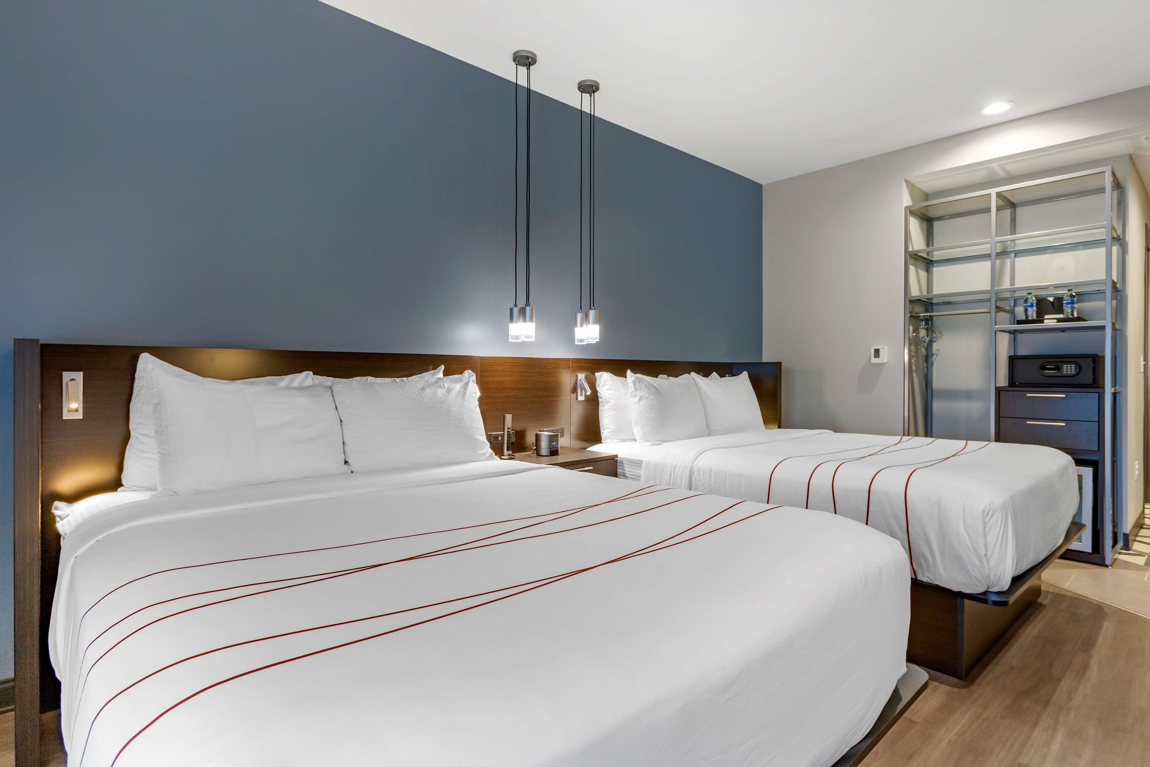 A hotel room with two beds, a minibar, and a built-in TV.