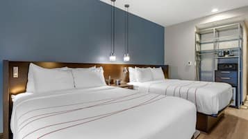 A hotel room with two beds, a minibar, and a built-in TV.