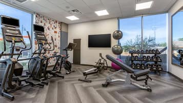 A gym with treadmills, elliptical machines, a bench press, and dumbbells.
