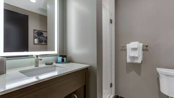 Un baño moderno con un espejo grande, un lavamanos, un inodoro y un perchero para toallas.