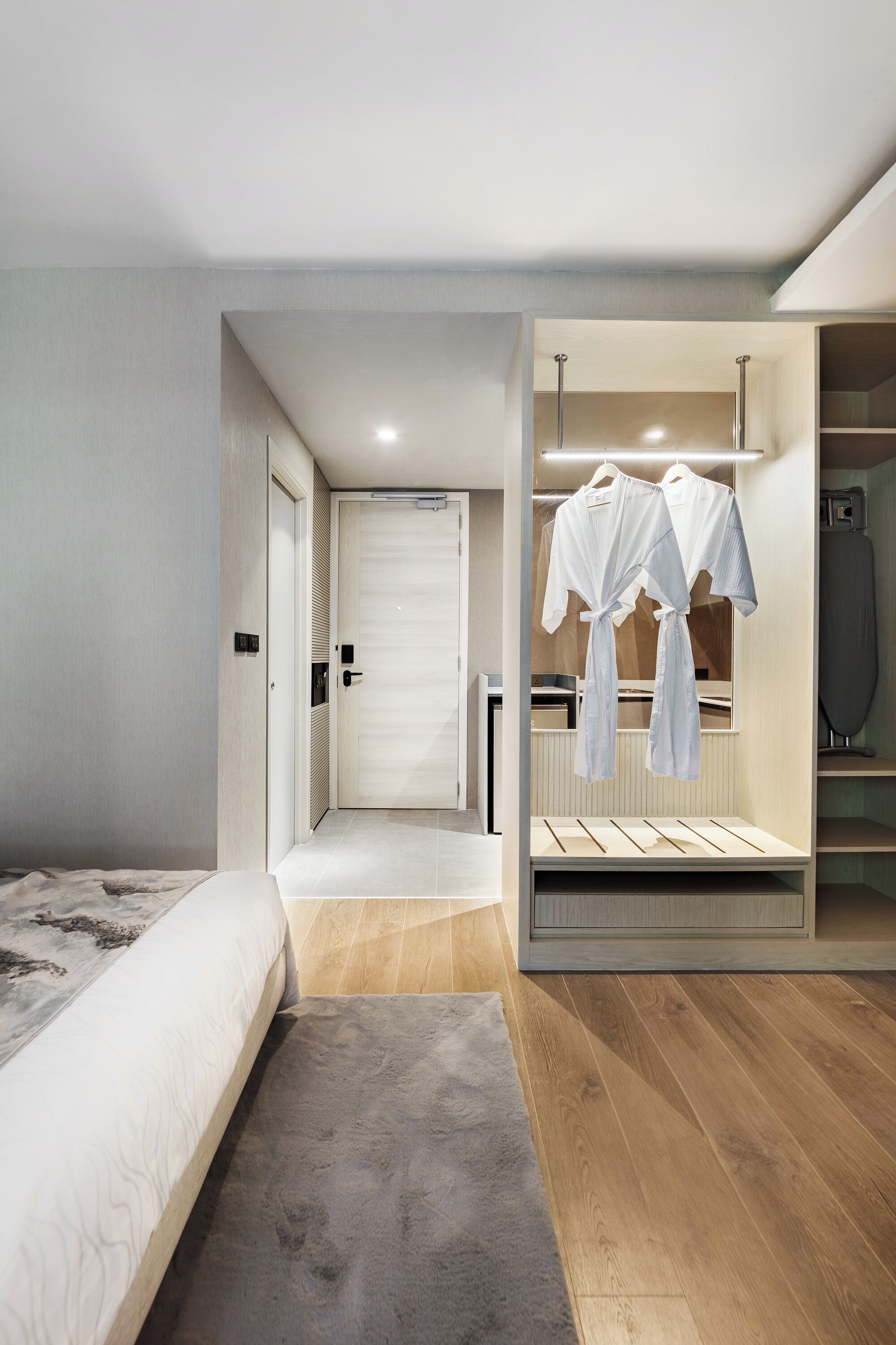 Une chambre moderne dotée d’un grand lit, d’un dressing et d’un espace repassage intégré.