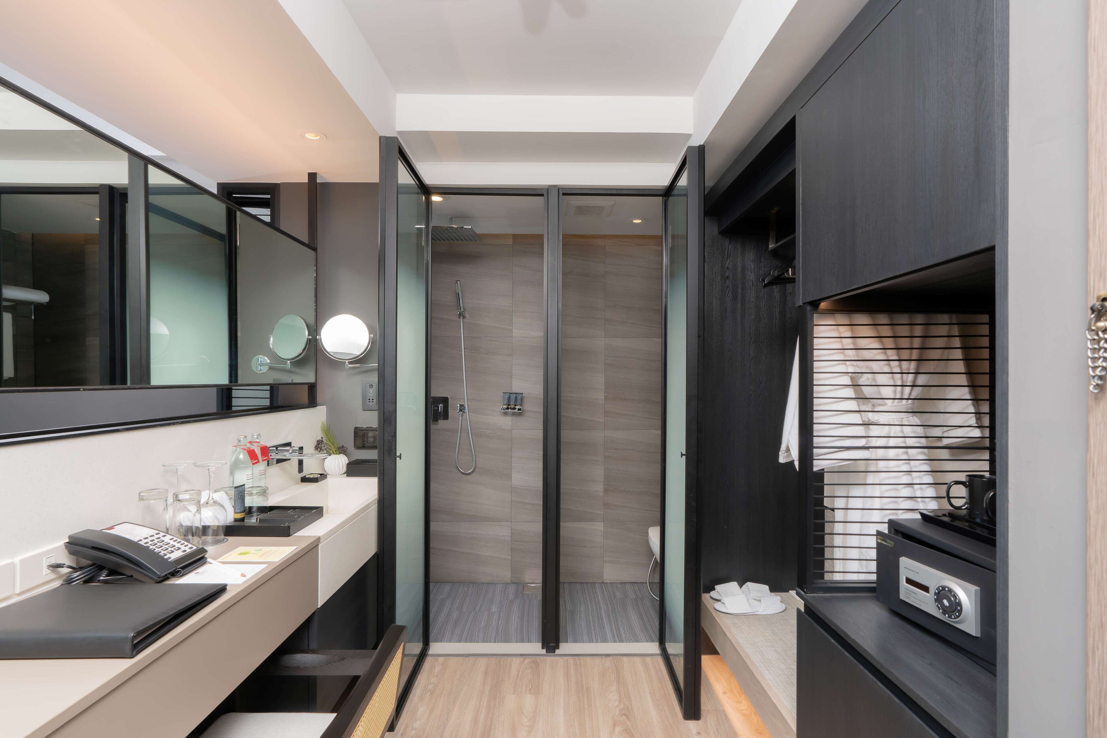 A modern bathroom with a shower, a vanity with a mirror, and a coffee machine.