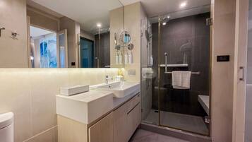 A modern bathroom with a glass-enclosed shower, a vanity with a sink, and a large mirror.