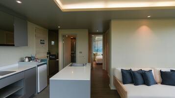 A modern kitchen with a central island, a dining area, and a bedroom with a bed and pillows.