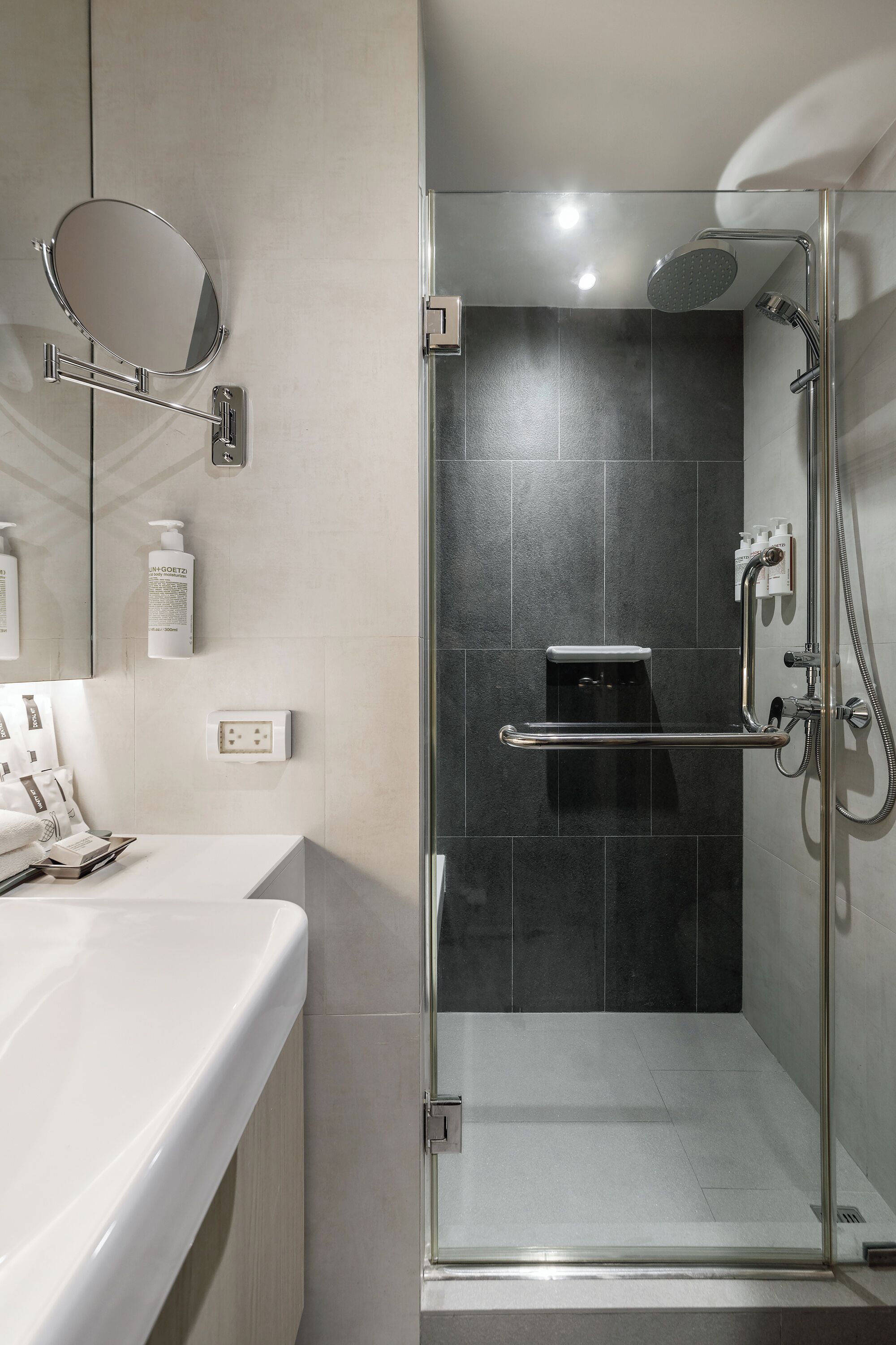 A modern bathroom with a glass-enclosed shower, a white sink, and a mirror.