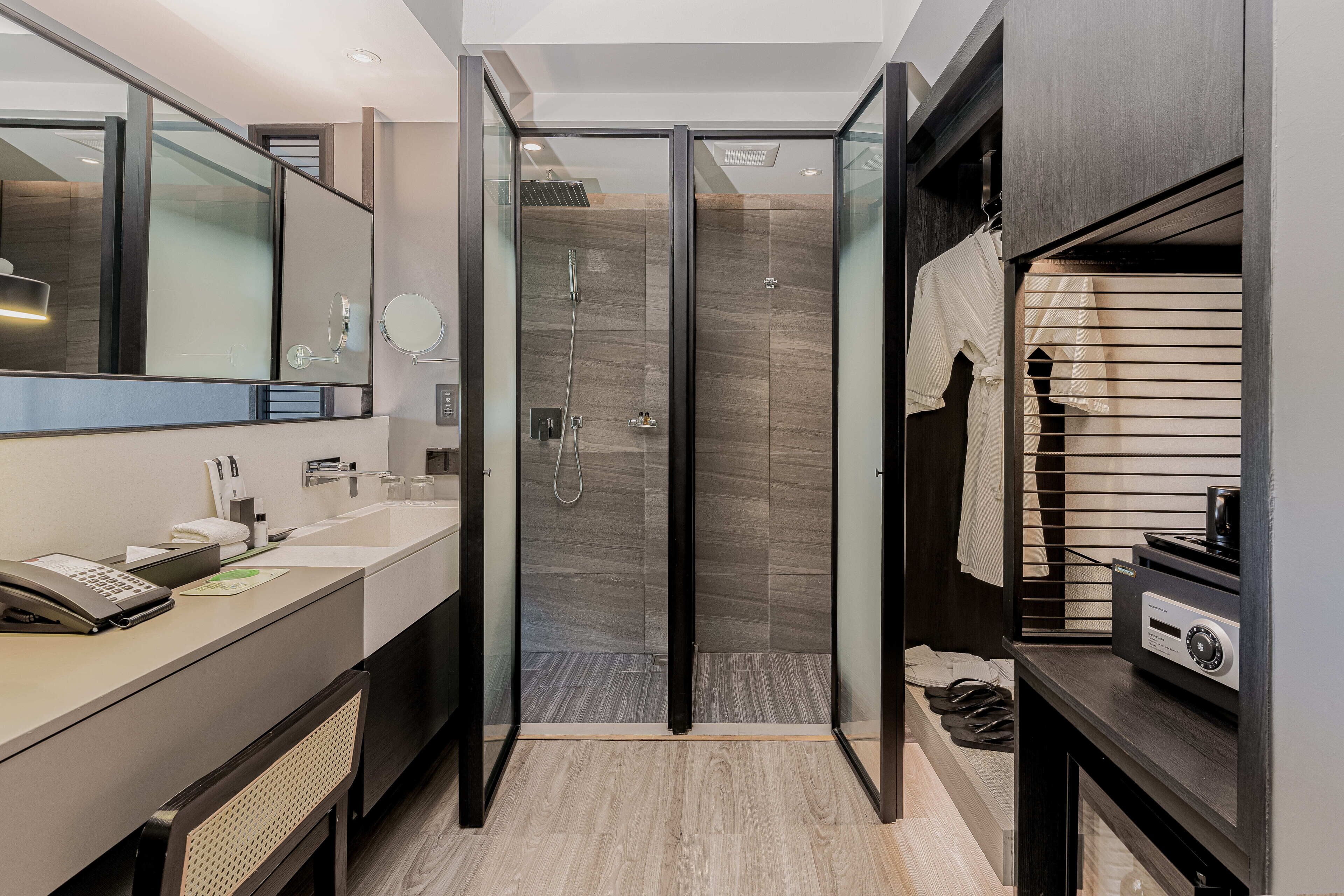Un baño moderno con ducha envuelta en vidrio, tocador con espejo y radio integrada.