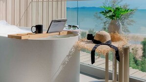 Een modern balkon met een gebogen bank, een laptop, een mok, en een tafeltje met een plant en een hoed.