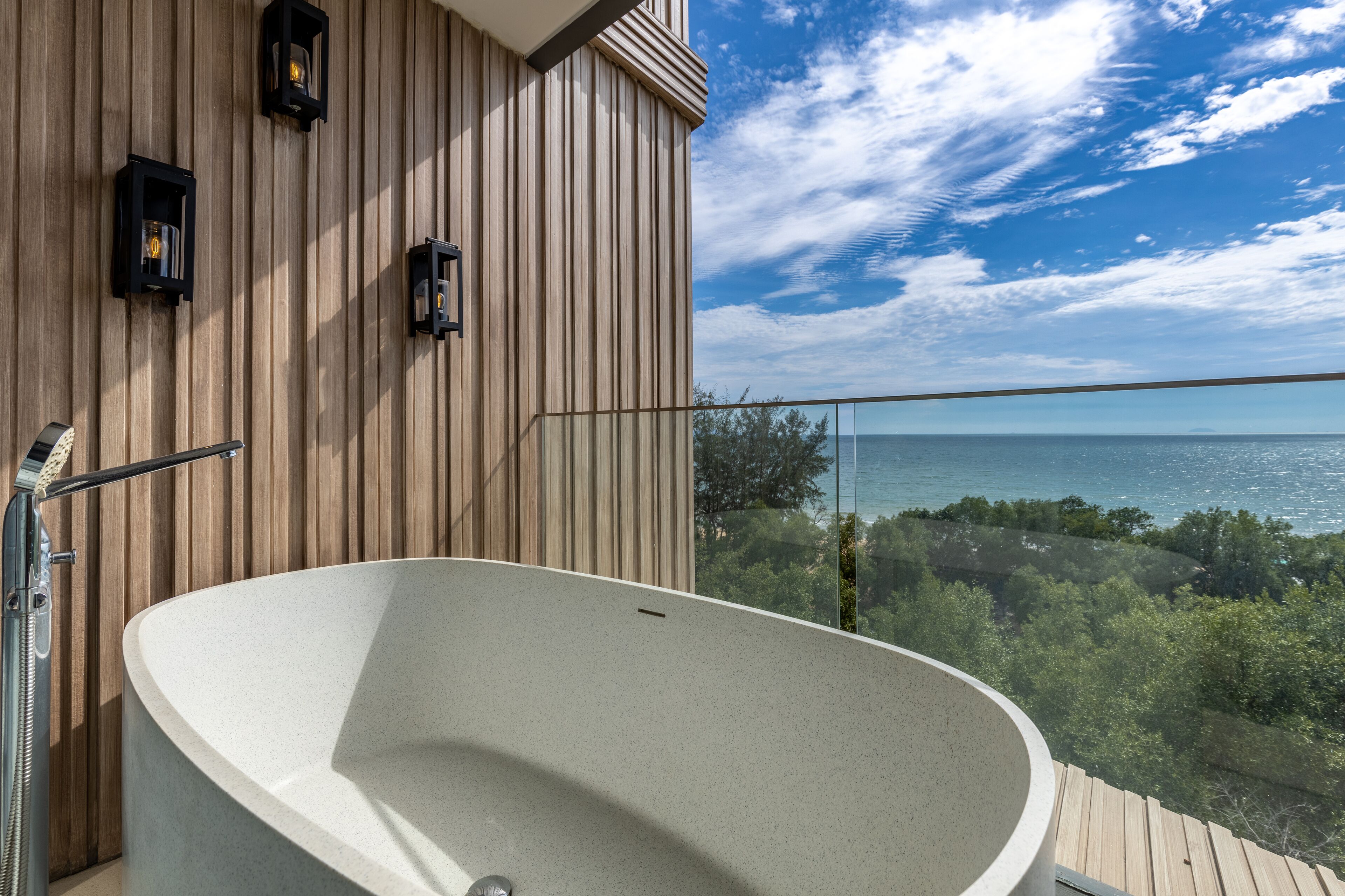Une salle de bain moderne avec une baignoire sur pieds, un lambris en bois et une vue sur la mer.