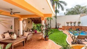 A covered patio area with a pool, seating, and potted plants.