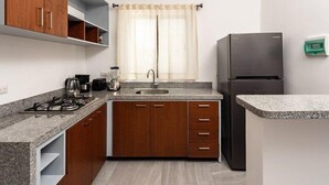 A kitchen with wooden cabinets, a granite countertop, a sink, a stove, and a refrigerator.