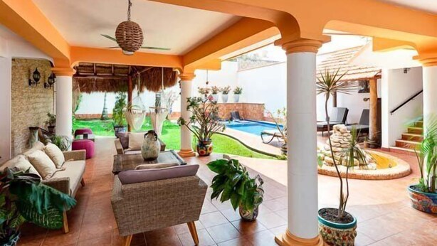 A spacious outdoor area with a pool, seating arrangements, and potted plants.