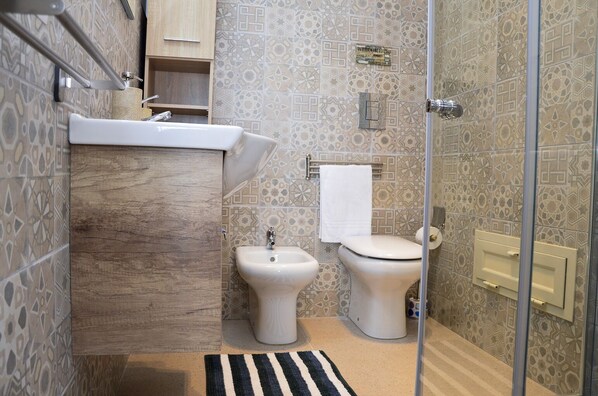 Casa de banho com lavatório, bidé, sanita e azulejos estampados.