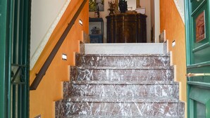 A staircase with a patterned carpet leading to a landing with a mirror and a decorative light fixture. - SUN SEA HOUSE TAORMINA  (Giardini Naxos)