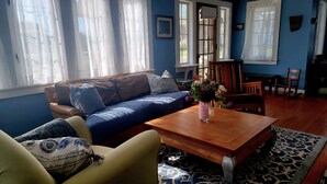 Ein Wohnzimmer mit einem blauen Sofa, einem Holztisch und einem gemusterten Teppich.