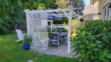A patio area with a white lattice arbor, outdoor furniture, and potted plants.