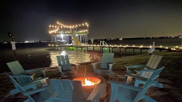 A fire pit surrounded by chairs on a patio with a view of a dock and water. - ❤️ Wide Open Water!  Huge Boat Dock w/ rope swing!  Lake toys (Kayak, Paddleboard, Lily Pad) included!  Great fishing!  🐟 (Gun Barrel City)
