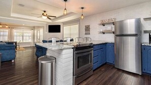 A modern kitchen with a central island, stainless steel appliances, and blue cabinetry. - ❤️ Wide Open Water!  Huge Boat Dock w/ rope swing!  Lake toys (Kayak, Paddleboard, Lily Pad) included!  Great fishing!  🐟 (Gun Barrel City)