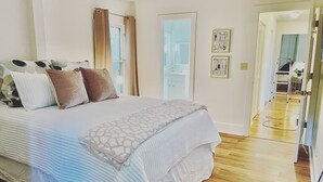 Ein Schlafzimmer mit einem Bett, einer Tür und einem Flur, der in einen weiteren Raum führt.