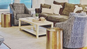Ein Wohnzimmer mit einer Couch, zwei Sesseln, einem Couchtisch und zwei metallenen Vasen.