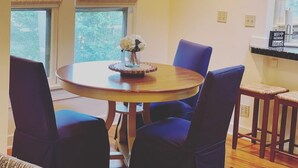 Ein Essbereich mit einem runden Tisch, blauen Stühlen und einer Blumenvase.
