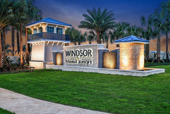 A resort sign with "Windsor Island Resort" written on it, surrounded by palm trees and a well-maintained lawn. - 7BR Disney Getaway ~ Private Pool & Spa ~ Resort (Davenport)
