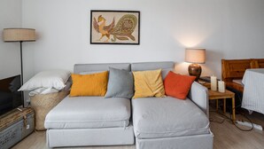 A modern living room with a grey sectional sofa, a woven basket, a lamp, and a framed artwork on the wall.