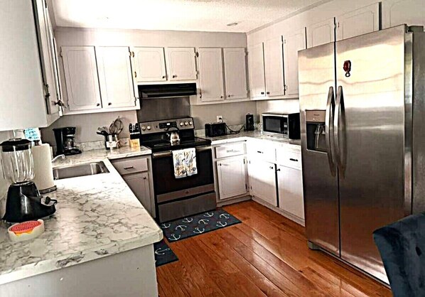 A kitchen with white cabinets, a stainless steel refrigerator, a stove, and a microwave.