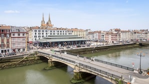 Eine Uferpromenade mit einer Brücke, historischen Gebäuden und einem markanten Kirchturm.