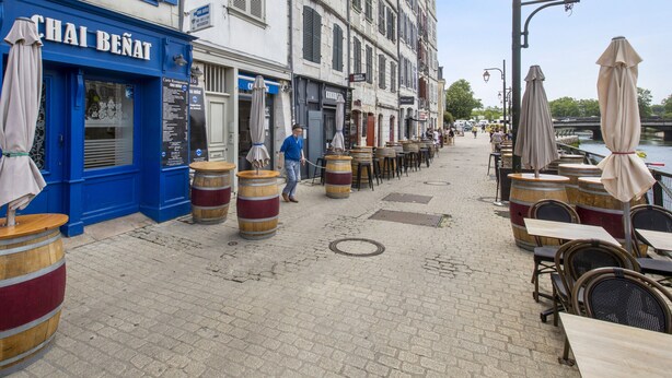 Eine Straße mit Außenbestuhlung, ein blaues Gebäude mit der Beschriftung 'CHAI BENAT' und ein Kanal im Hintergrund.