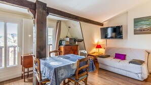 Una sala de estar acogedora con comedor, muebles de madera, un televisor de pantalla plana y un cuadro en la pared.